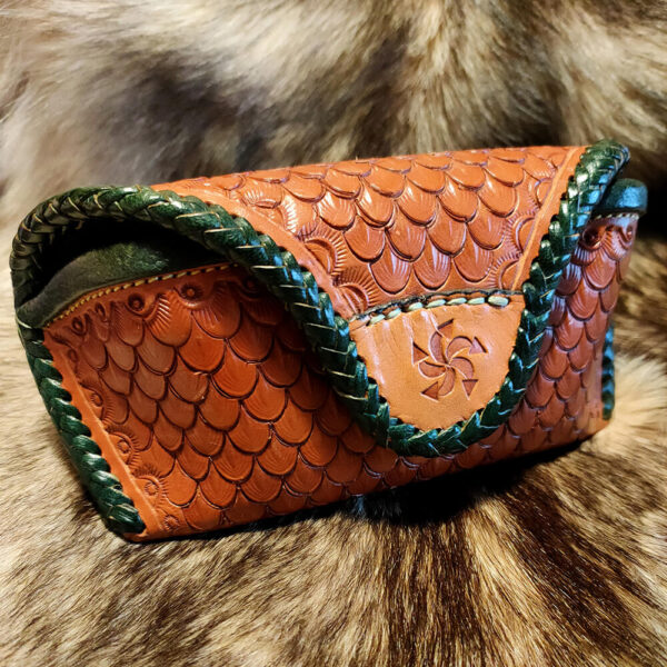 Funda de gafas mateada con escamas y borde trenzado verde.